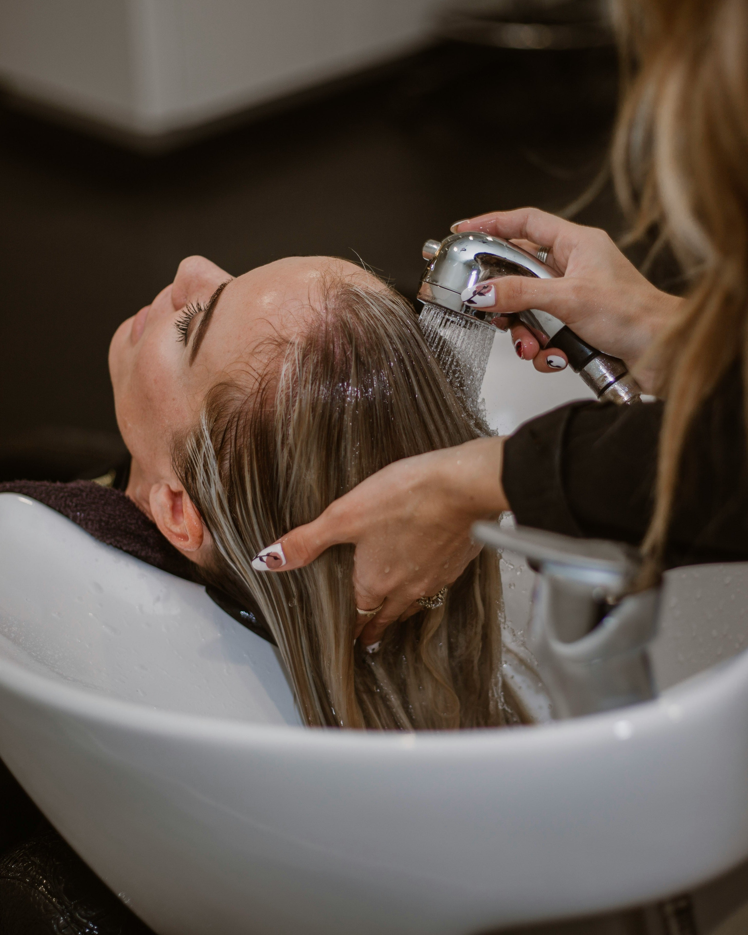 Person getting hair washed at a salon with a hairdresser.